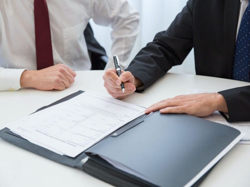 Two professionals reviewing documents and signing papers. Two professionals reviewing documents and signing papers.